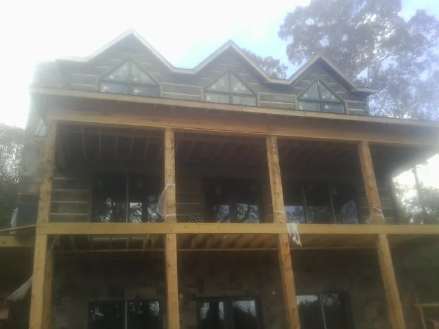 Dormers and porch framing on a large log home under construction — Roof Coating work by our crew in Augusta